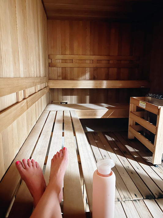 Woman’s feet with nail polish in a dry sauna with pink water bottle